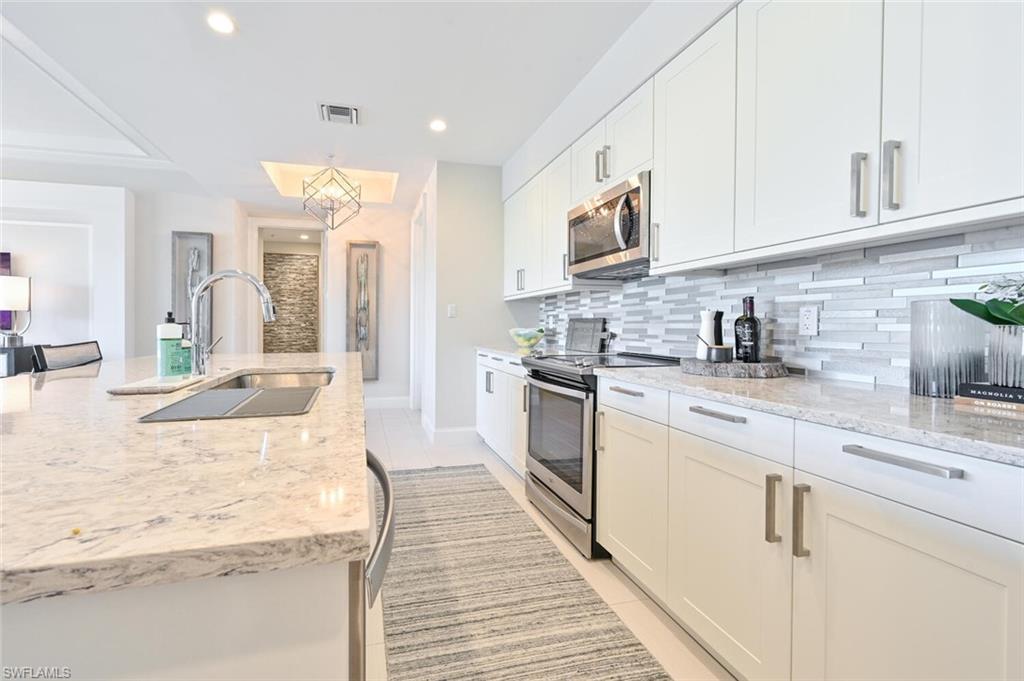 1111 Central Avenue, Unit 303 Naples, FL 34102 - Photo 15 of 50 a kitchen with stainless steel appliances granite countertop a lot of counter space and wooden floors