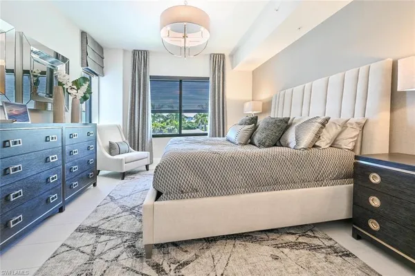 a bedroom with a large bed and a large mirror on dresser and a large window