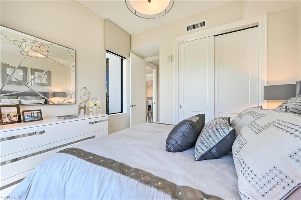 1111 Central Avenue, Unit 303 Naples, FL 34102 - Photo 23 of 50 a bedroom with a large bed and a chandelier