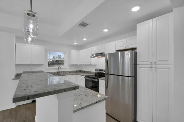 a kitchen with granite countertop a refrigerator a sink a stove a dining table and chairs