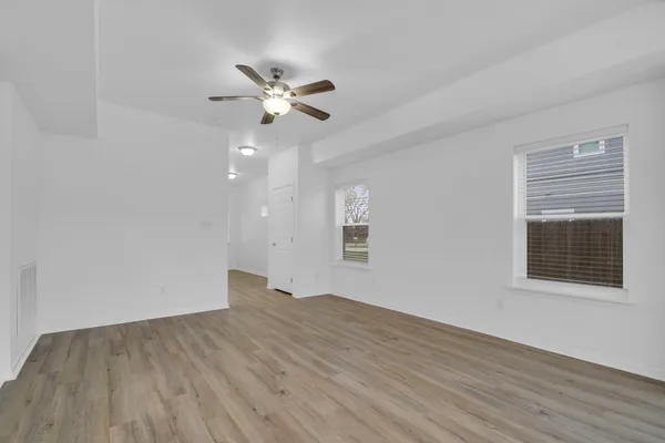a view of empty room with wooden floor and fan