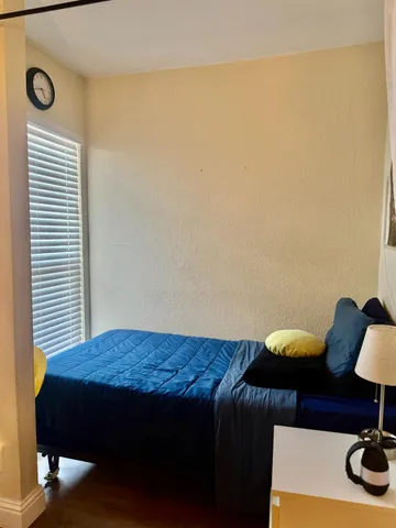 a bedroom with a bed and a lamp on dresser