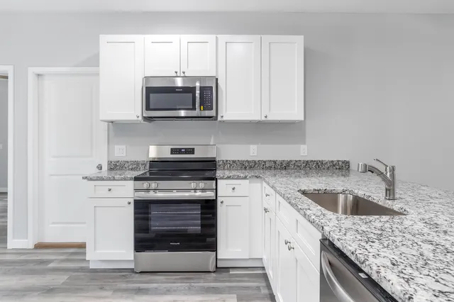 a kitchen with granite countertop a stove sink and microwave
