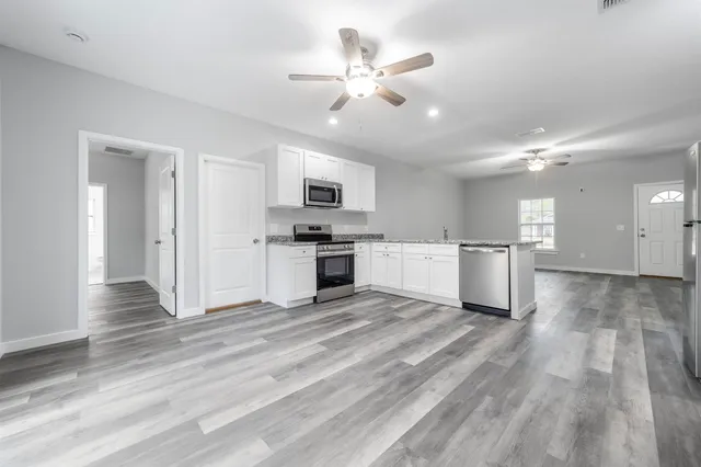 a view of a kitchen with a sink and dishwasher a stove top oven with white cabinets