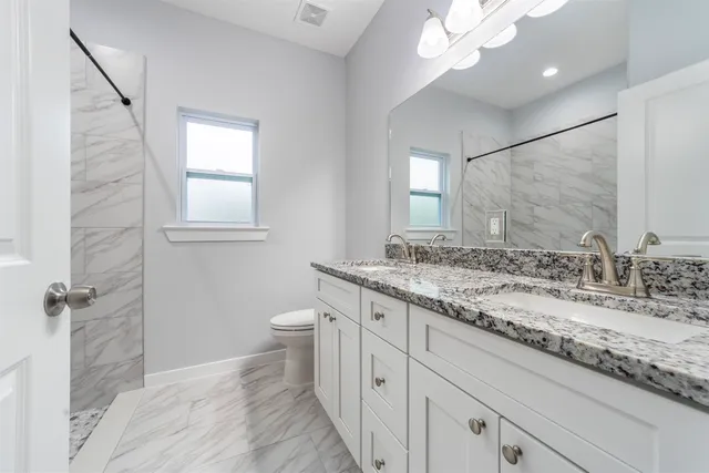 a bathroom with a granite countertop sink a toilet and a mirror