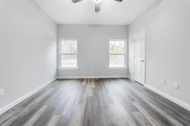 an empty room with wooden floor and windows