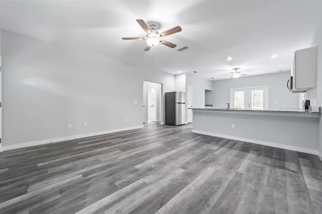 an empty room with a ceiling fan and wooden floor