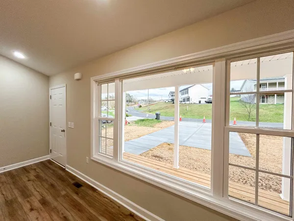 a view of an empty room with wooden floor and a kitchen