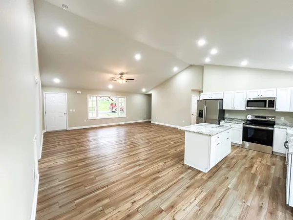a view of an empty room with wooden floor and a ceiling fan