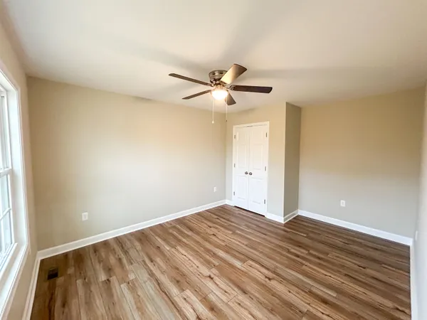 a view of empty room with wooden floor and fan