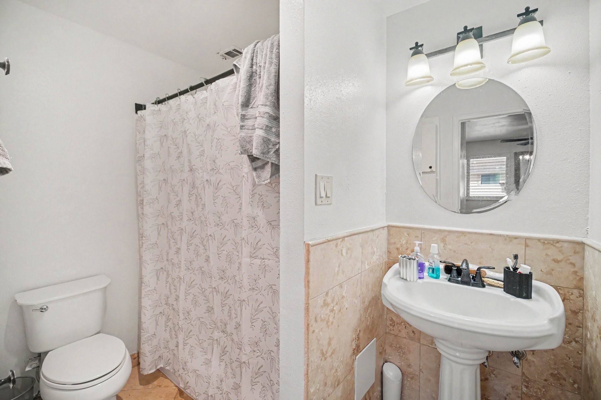 5801 Lumberdale Road, Unit 78 Houston, TX 77092 - Photo 29 of 35 Charming bathroom with a pedestal sink, elegant round mirror, and modern lighting. The shower area features a stylish curtain, and there are tasteful tile accents throughout.