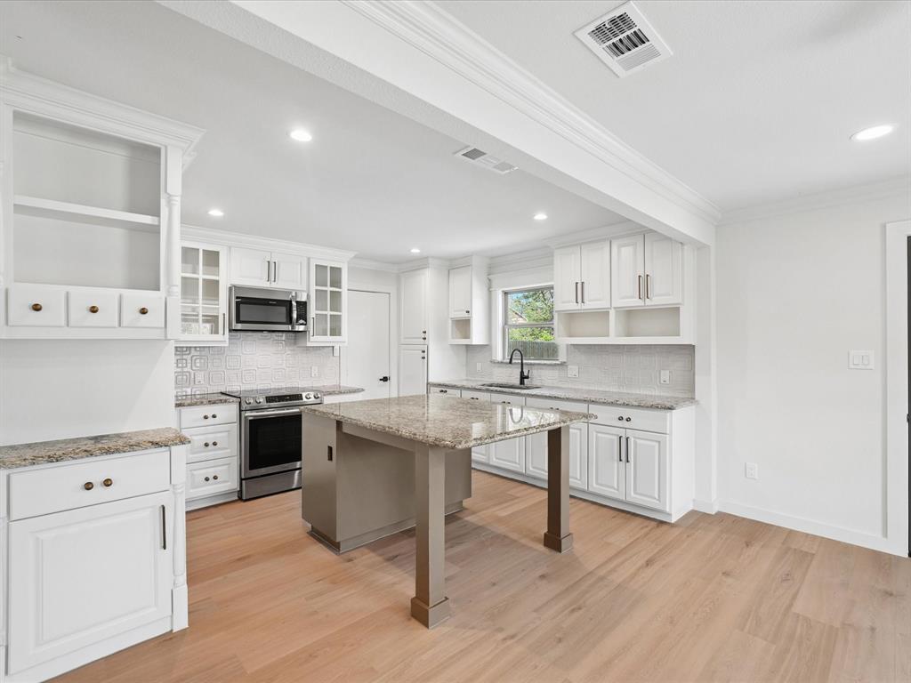 5544 Ranchero Lane Dallas, TX 75236 - Photo 6 of 21 a kitchen with stainless steel appliances a stove a sink dishwasher a refrigerator white cabinets and wooden floor