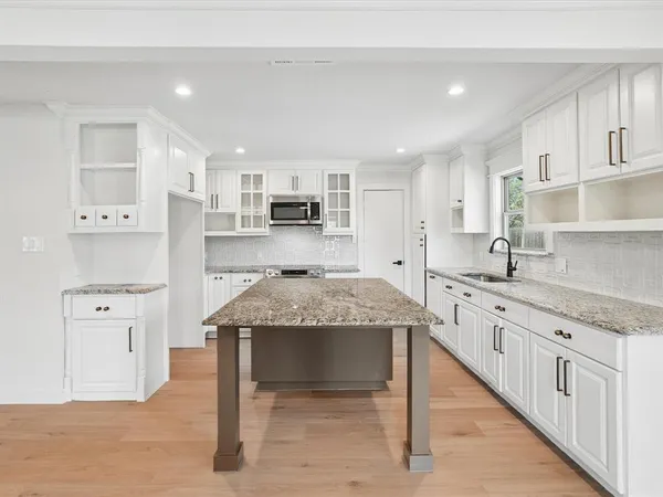 a kitchen with stainless steel appliances granite countertop a table chairs sink and cabinets