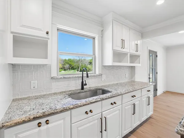 a kitchen with granite countertop a sink window and cabinets