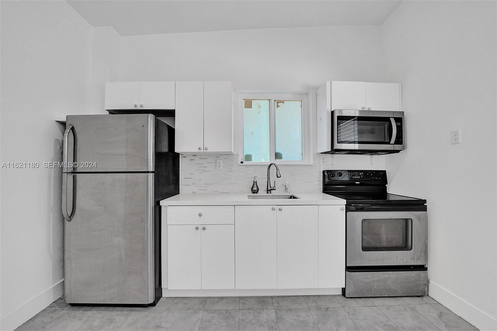 418 Northwest 47th Street Miami, FL 33127 - Photo 15 of 24 a kitchen with stainless steel appliances white cabinets and a refrigerator