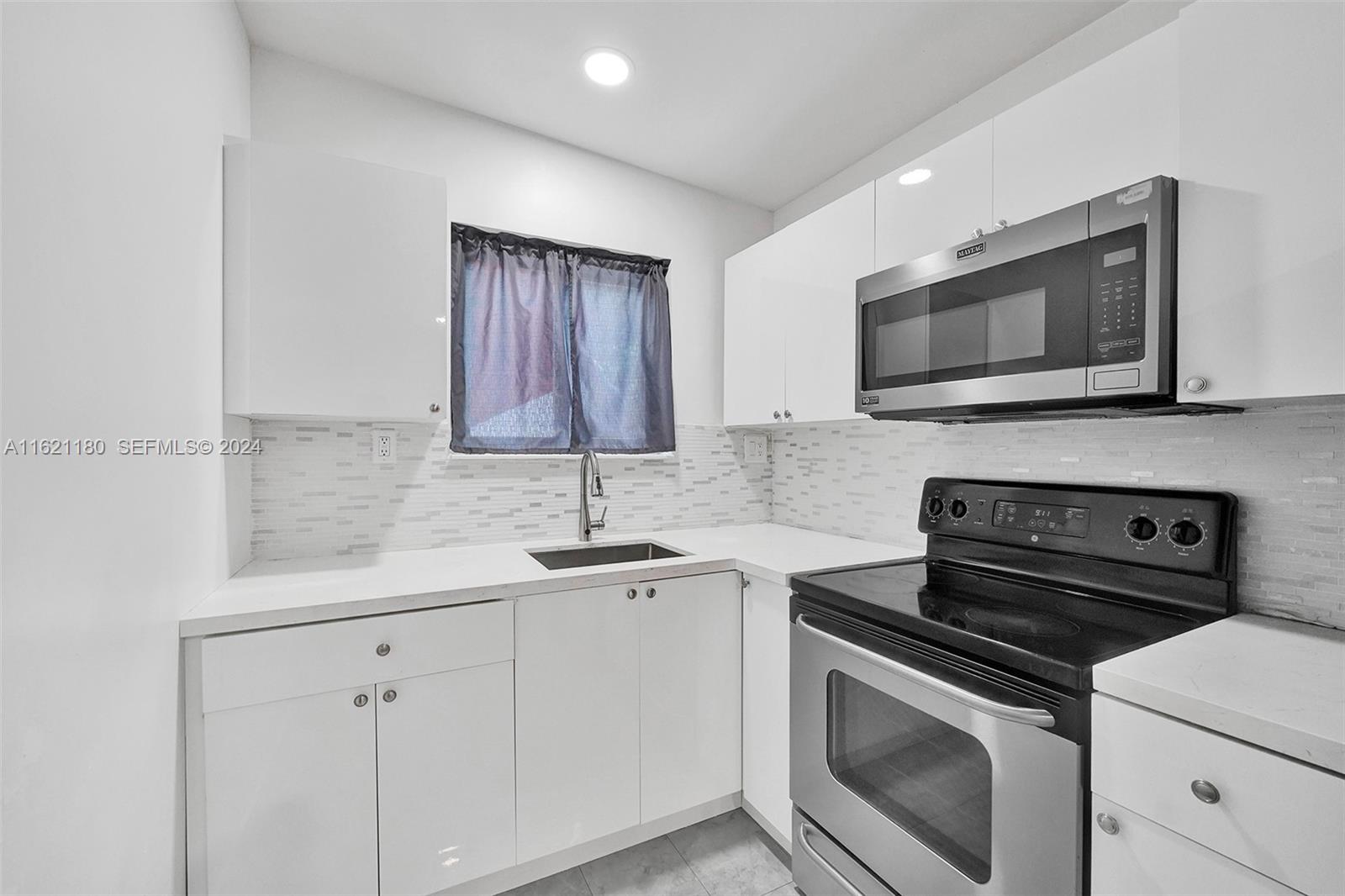 418 Northwest 47th Street Miami, FL 33127 - Photo 20 of 24 a kitchen with granite countertop white cabinets sink and stainless steel appliances