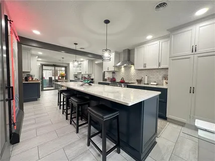 a kitchen with stainless steel appliances kitchen island granite countertop a table chairs and a refrigerator