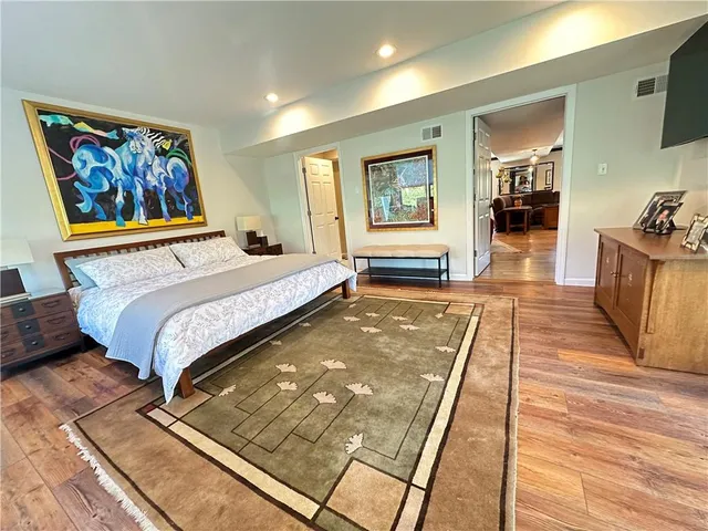 a spacious bedroom with a large bed a rug and paintings on the wall