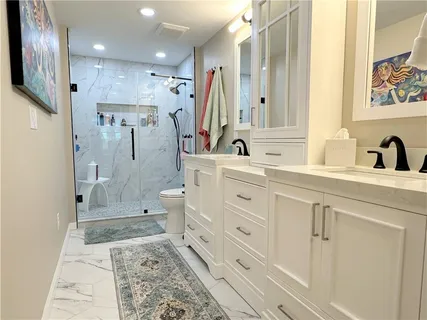 a bathroom with a double vanity sink a toilet a mirror and shower