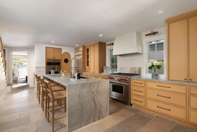 a kitchen with stainless steel appliances granite countertop a stove top oven a sink dishwasher a dining table and chairs with wooden floor