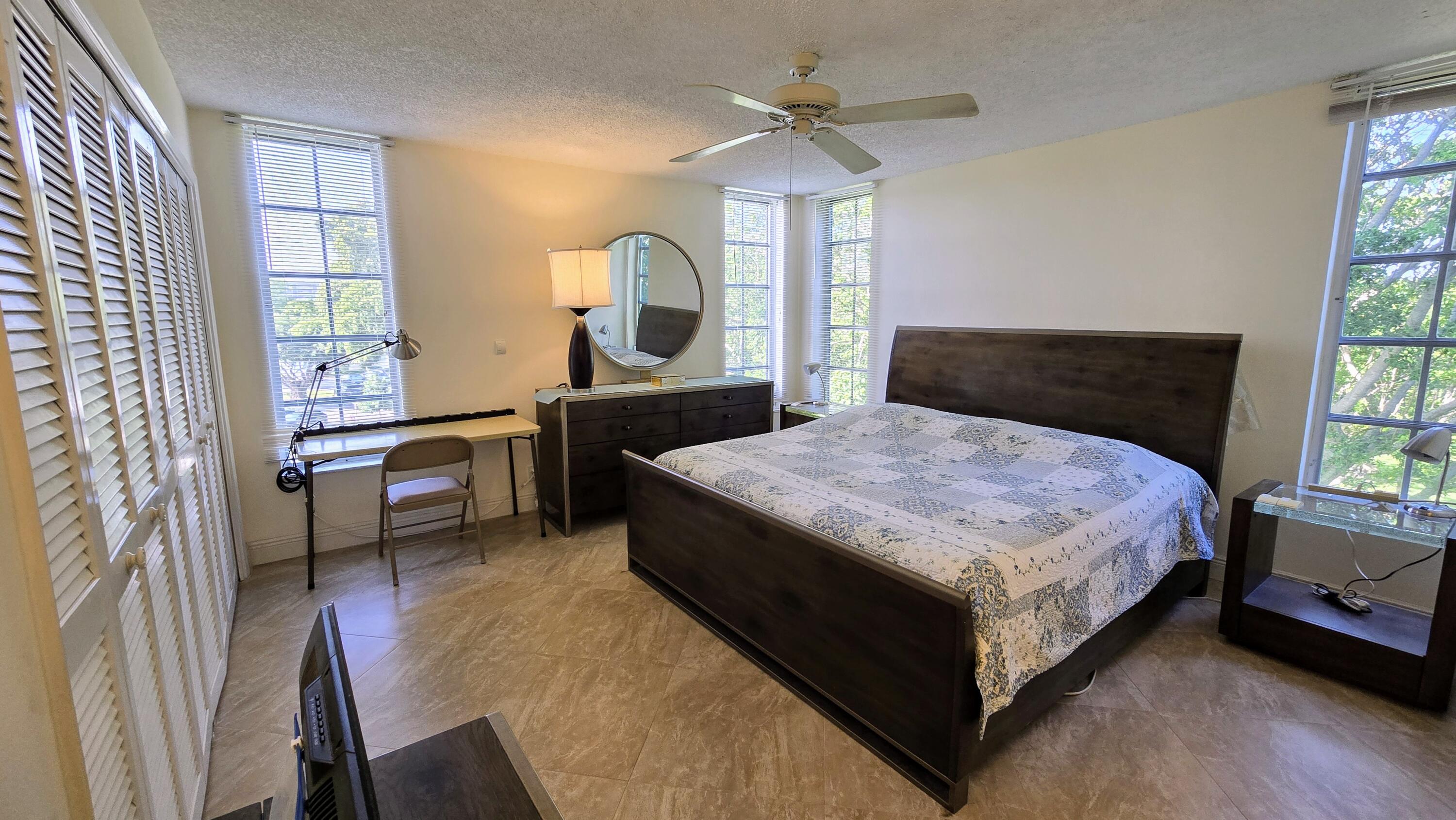 3100 North Course Lane, Unit 410 Pompano Beach, FL 33069 - Photo 12 of 23 a bedroom with a bed a mirror on dresser and a window