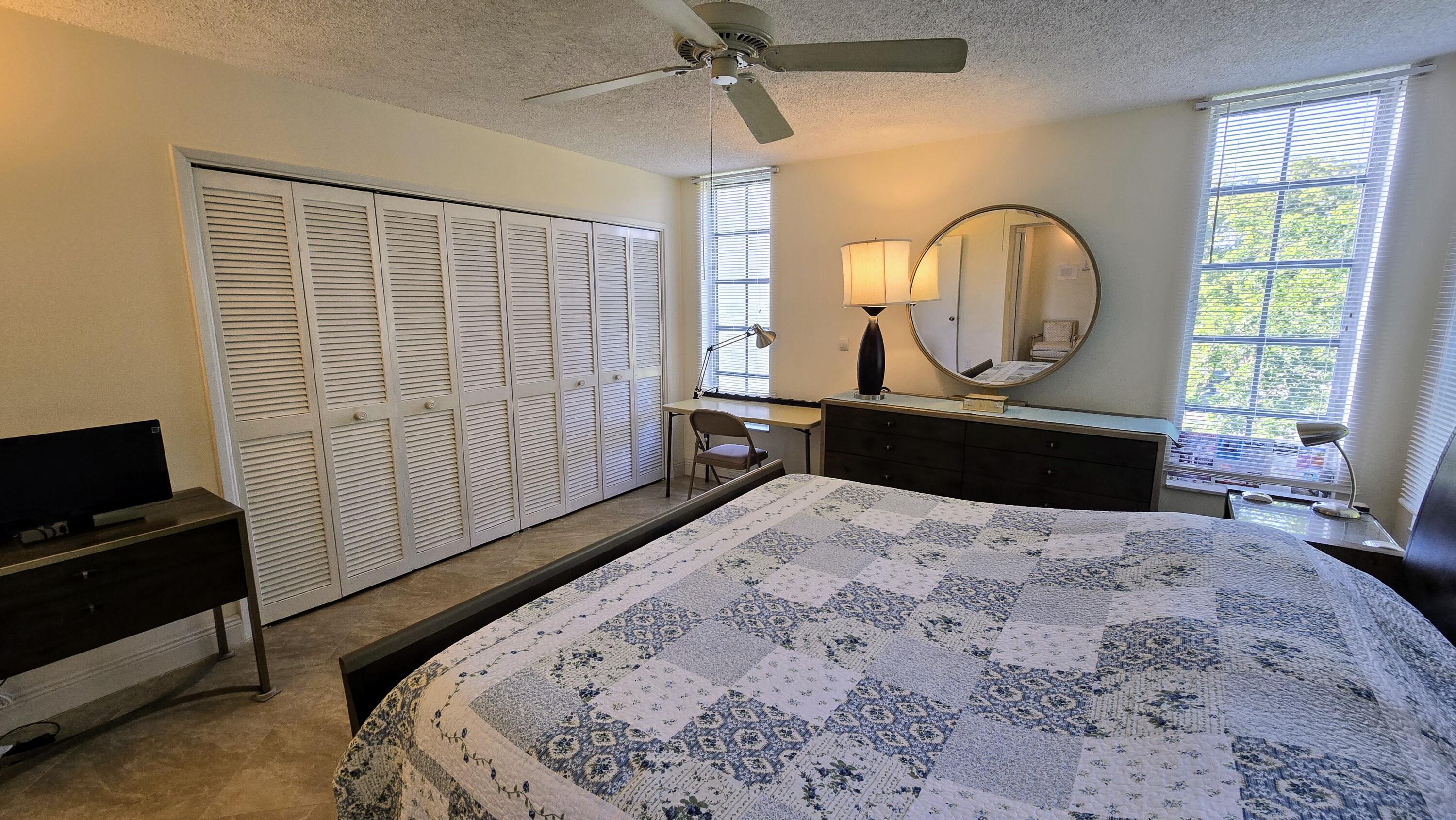 3100 North Course Lane, Unit 410 Pompano Beach, FL 33069 - Photo 13 of 23 a bedroom with a bed a mirror on dresser and a large window