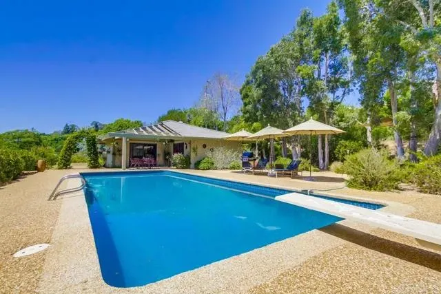 a view of a swimming pool with lawn chairs under an umbrella