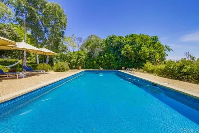 17355 Avenida De Acacias Rancho Santa Fe, CA 92067 - Photo 12 of 16 a view of a swimming pool with lawn chairs under an umbrella
