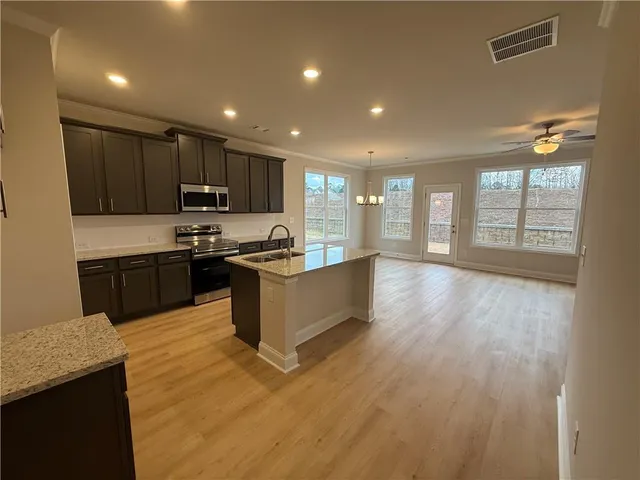 a large kitchen with stainless steel appliances kitchen island granite countertop a stove a sink and a microwave