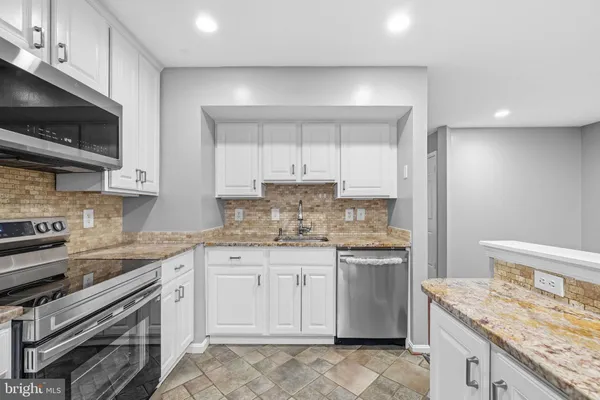 a kitchen with granite countertop a stove sink and microwave