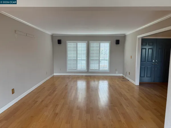 an empty room with wooden floor and windows