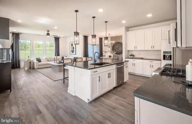 a kitchen with stainless steel appliances granite countertop wooden floors wooden cabinets a center island and a window