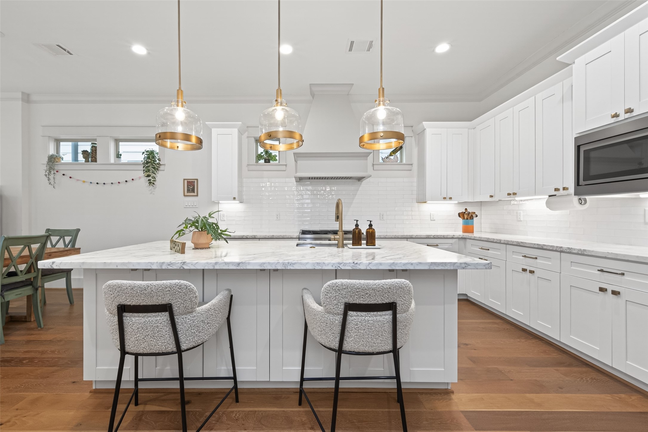 515 West 25th Street Houston, TX 77008 - Photo 10 of 35 Kitchen island features a single-basin stainless steel undermount sink, three Park Harbor antique brass downlight pendants, and a Brilliance Champagne Bronze Delta faucet with pull-out sprayer.