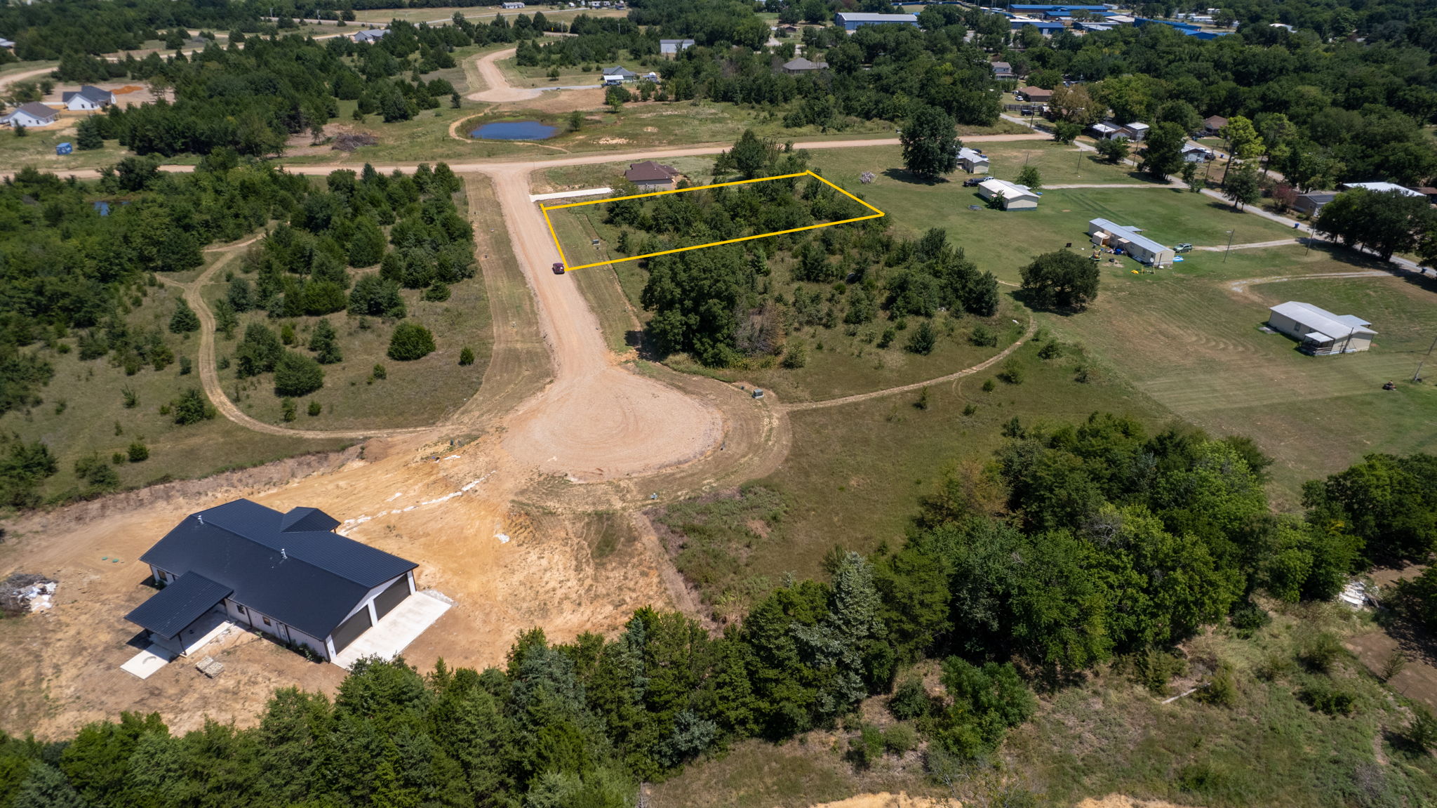 0 Redbird Lane Colbert, OK 74733 - Photo 4 of 6 Expansive lot featuring a yellow-outlined boundary, surrounded by mature trees, and a developed residential road