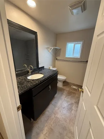 a bathroom with a granite countertop sink a toilet and a mirror