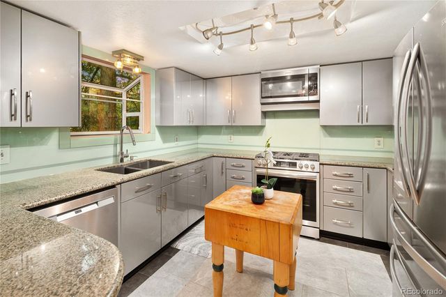 a kitchen with granite countertop a sink and a white wooden cabinets