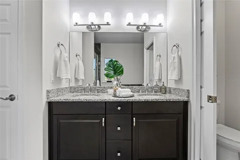 a bathroom with a granite countertop sink toilet and mirror