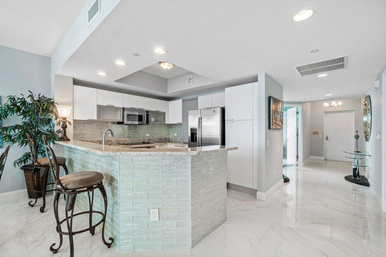 2640 Lake Shore Drive, Unit 1216 Riviera Beach, FL 33404 - Photo 11 of 60 a kitchen with stainless steel appliances kitchen island granite countertop a refrigerator and a stove top oven