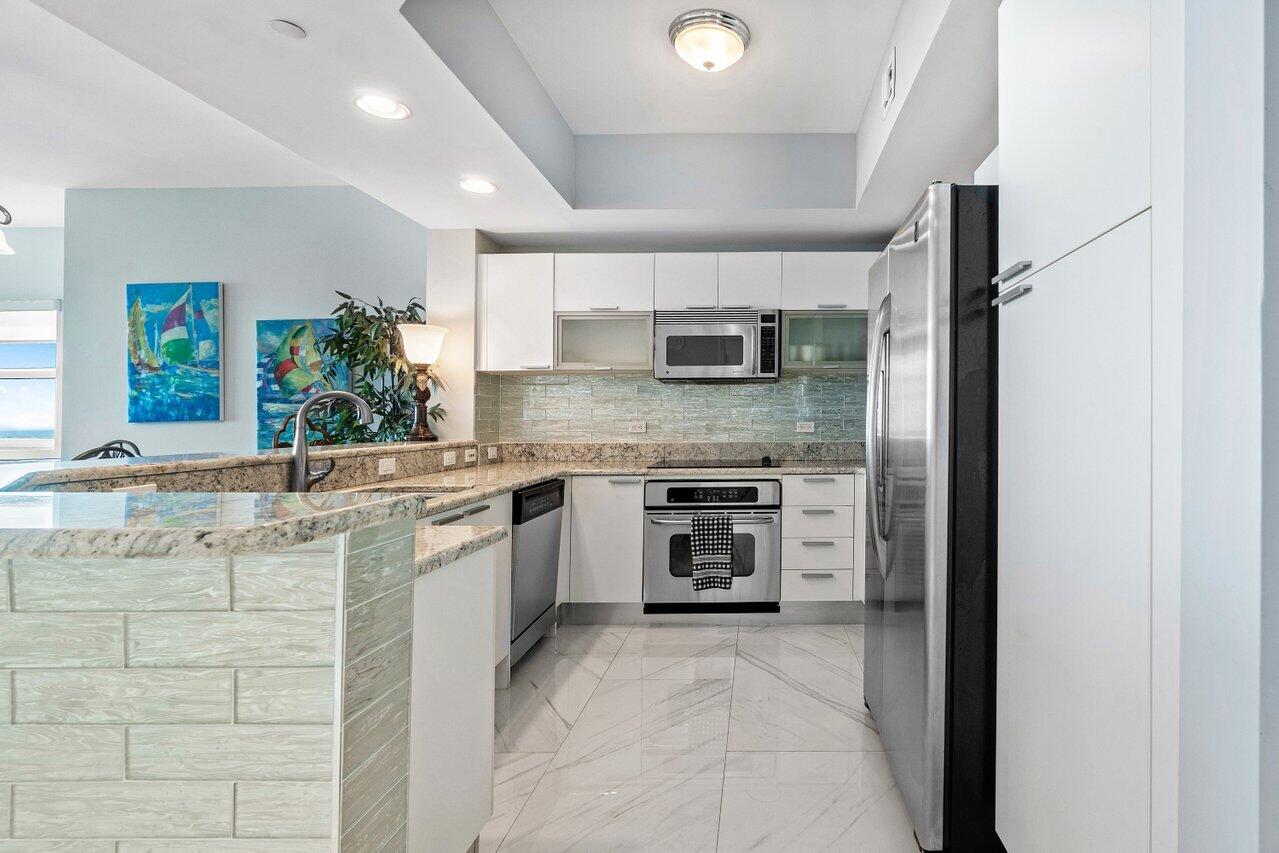 2640 Lake Shore Drive, Unit 1216 Riviera Beach, FL 33404 - Photo 13 of 60 a kitchen with stainless steel appliances granite countertop a stove sink and cabinets