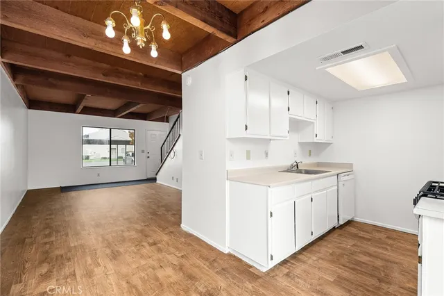 a kitchen that has a lot of white cabinets and wooden floor