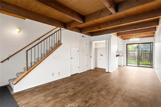 a view of an empty room with wooden floor and stairs