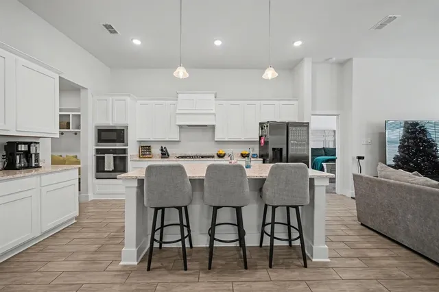 a kitchen with microwave a refrigerator and chairs