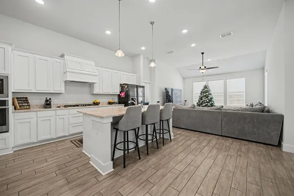 a kitchen with stainless steel appliances granite countertop wooden floor sink table and chairs