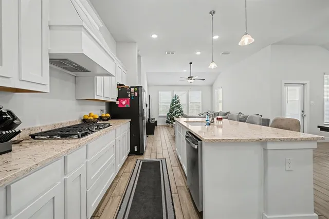 a kitchen with granite countertop a sink stove and cabinets