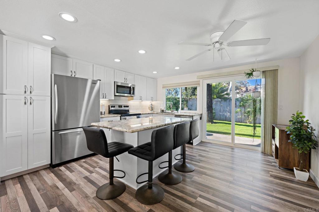 3681 Harvard Drive Oceanside, CA 92056 - Photo 8 of 30 a kitchen with stainless steel appliances granite countertop a refrigerator a stove a sink a dining table and chairs with wooden floor