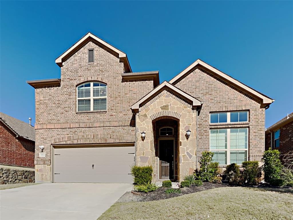 View of front of property featuring brick siding, driveway, and stone siding