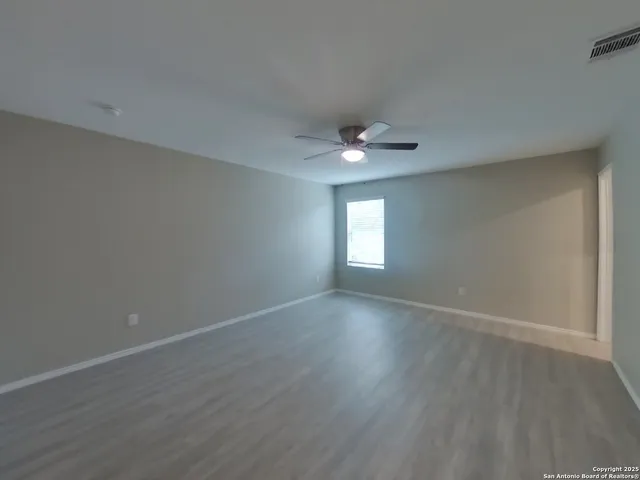 a view of an empty room with a window and wooden floor