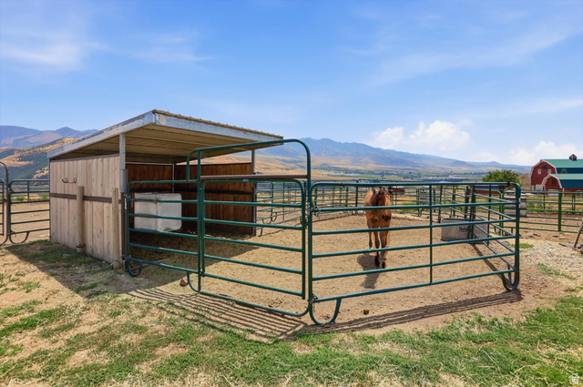 715 Ranch Loop Road Preston, ID 83263 - Photo 52 of 77 Paddock with a wood-sided lean-to shelter, metal fencing, and a red barn structure in the background