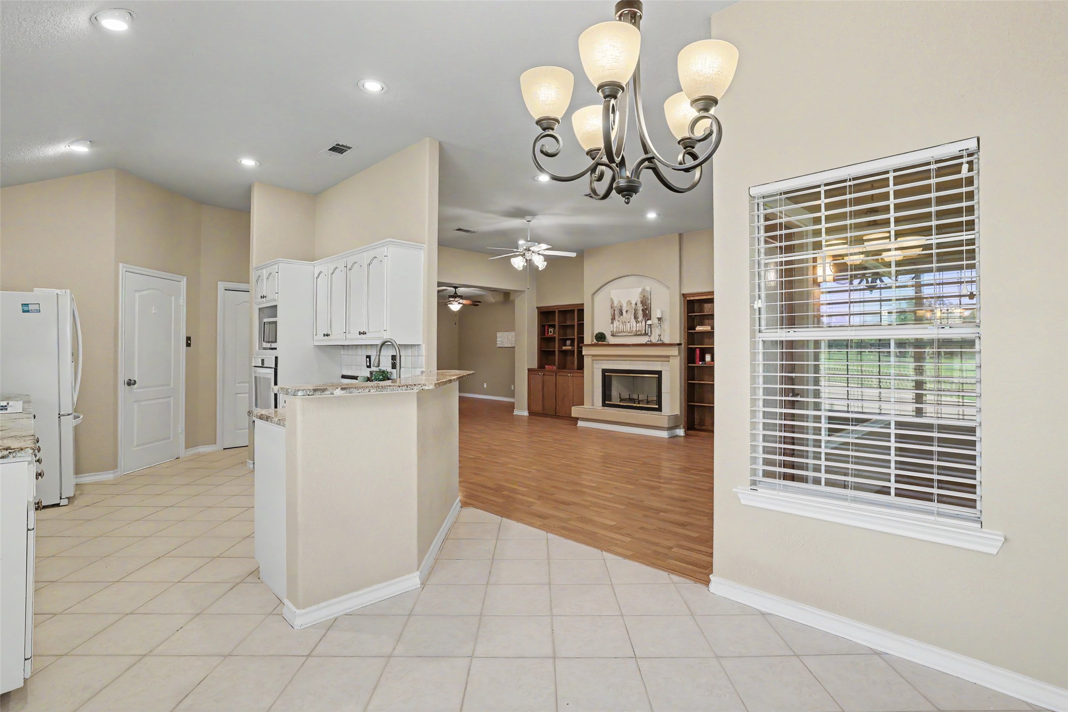 30107 Hamlet Circle Georgetown, TX 78628 - Photo 9 of 40 A graceful chandelier illuminates the seamless transition from kitchen to the comfortable living area with fireplace and built-in shelving.