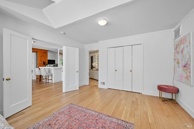a view of a livingroom with wooden floor and a refrigerator